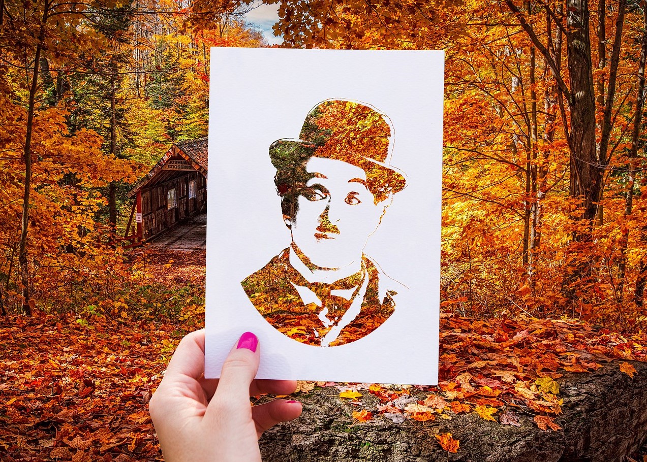 Cut-out van Charlie Chaplin tegen herfstbos in de achtergrond