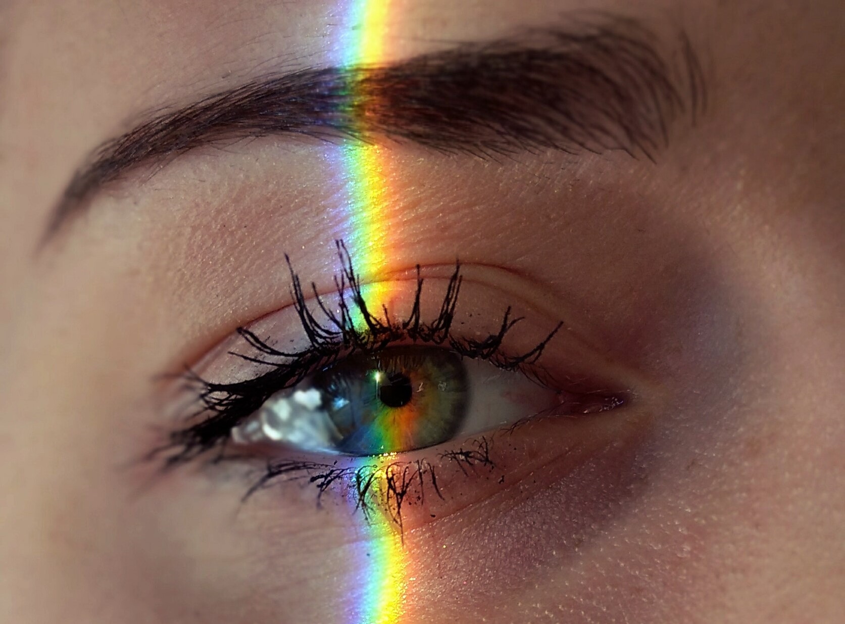 Close-up van oog waar lichtstreep in regenboogkleuren doorheen loopt