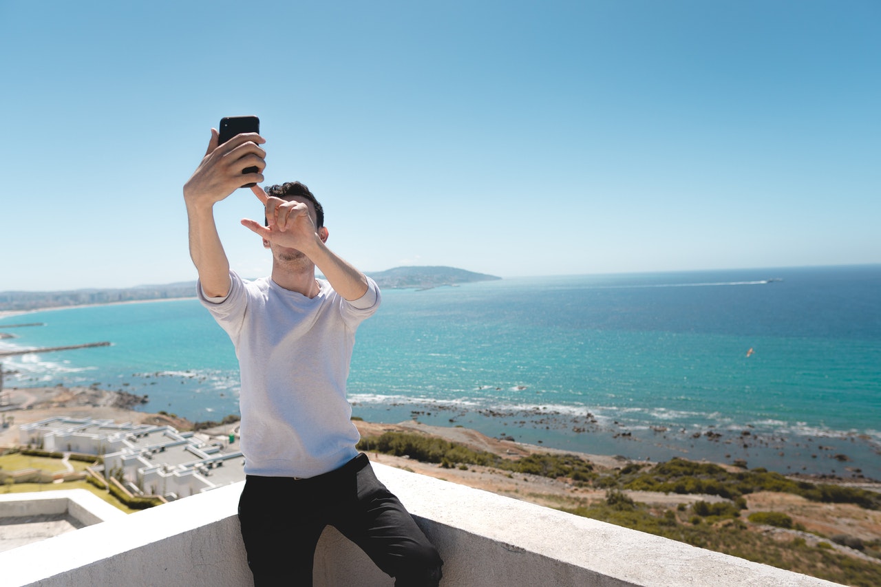 Man trekt selfie aan azuurblauwe zee en mooi strand