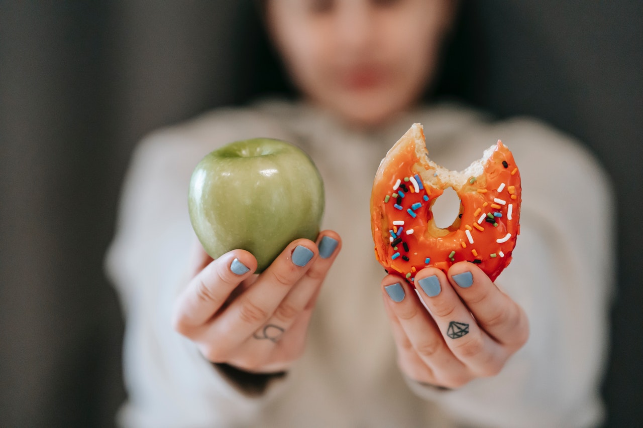 vrouw toont appel en donut en kan niet kiezen