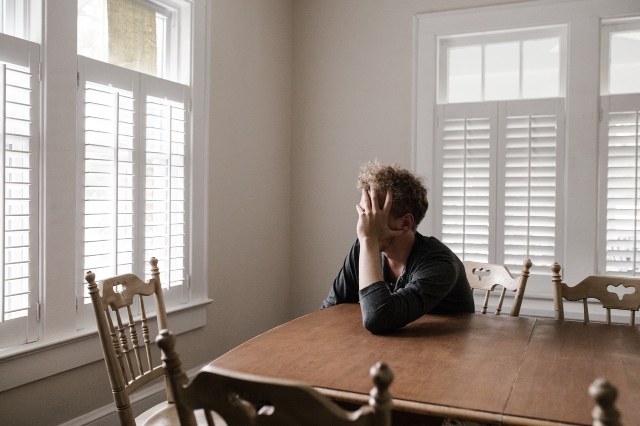 Man aan keukentafel verbergt hoofd in hand