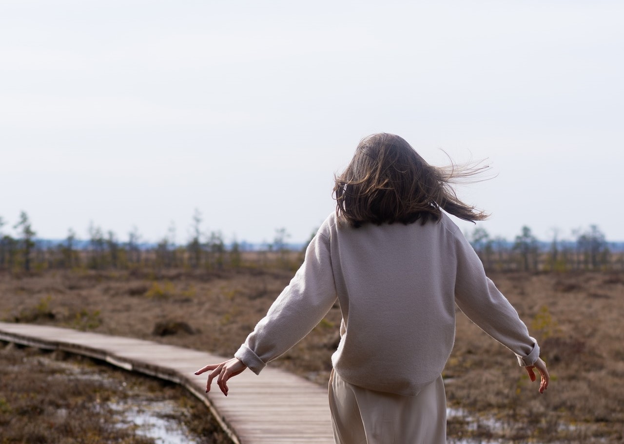 Dame loopt in de wind op een vlonderpad