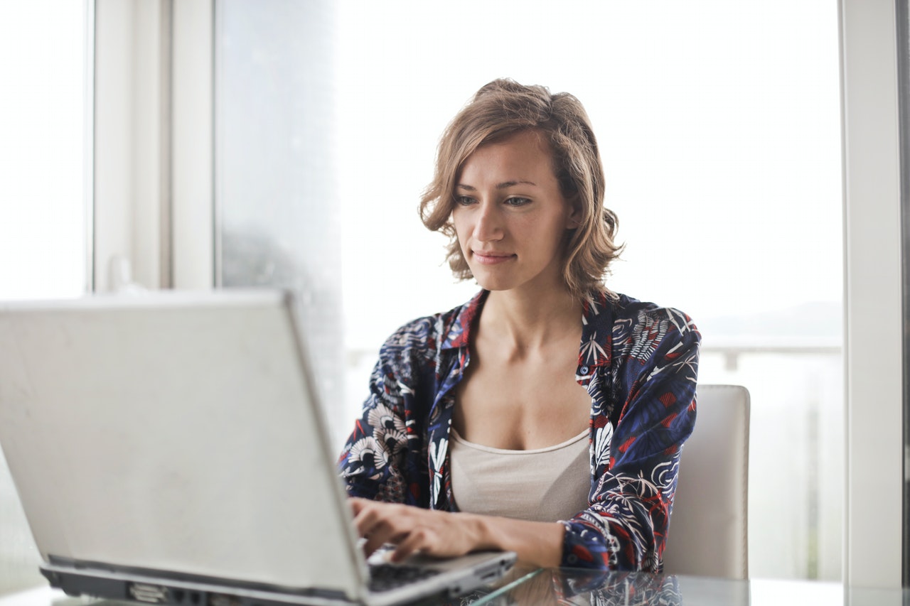 Vrouw met bloemetjesblouse werkt aan laptop