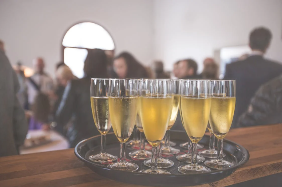 schotel met fluitglazen cava, op de achtergrond mensen