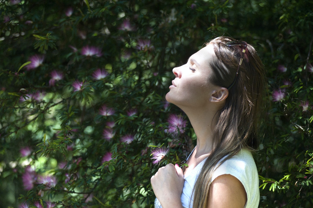 Vrouw bij struik ademt frisse lucht in